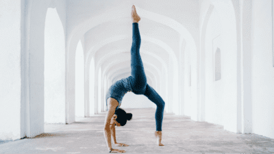 woman doing a yoga exercise backbend in front of white archway
